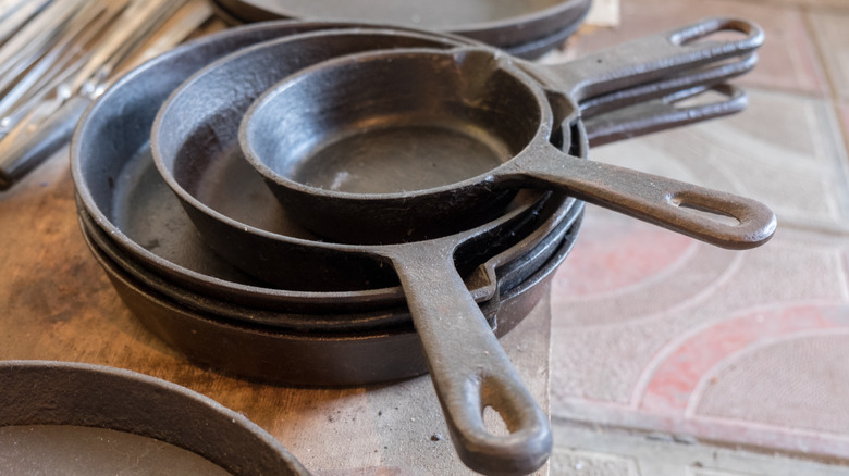 A stack of dusty cast iron pans at a flea market