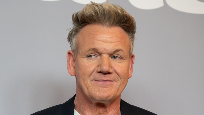 Gordon Ramsay poses on a red carpet in a dark suit jacket and white t-shirt