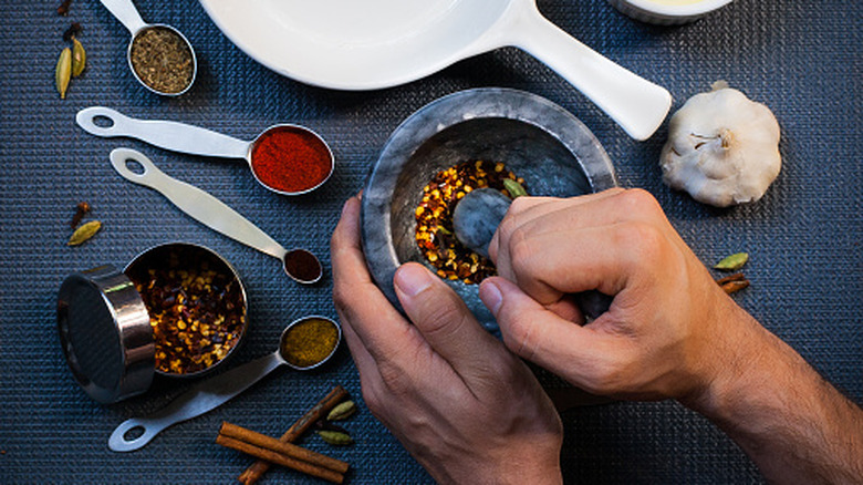Hands grinding spices in mortar and pestle