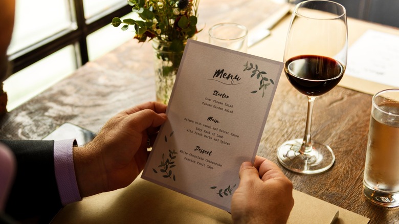 Person holding a menu at a table in a restaurant