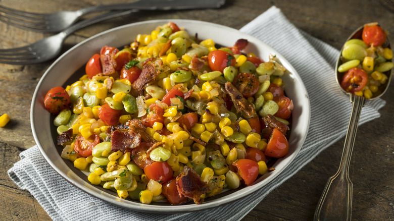 Bowl of succotash with spoon and forks
