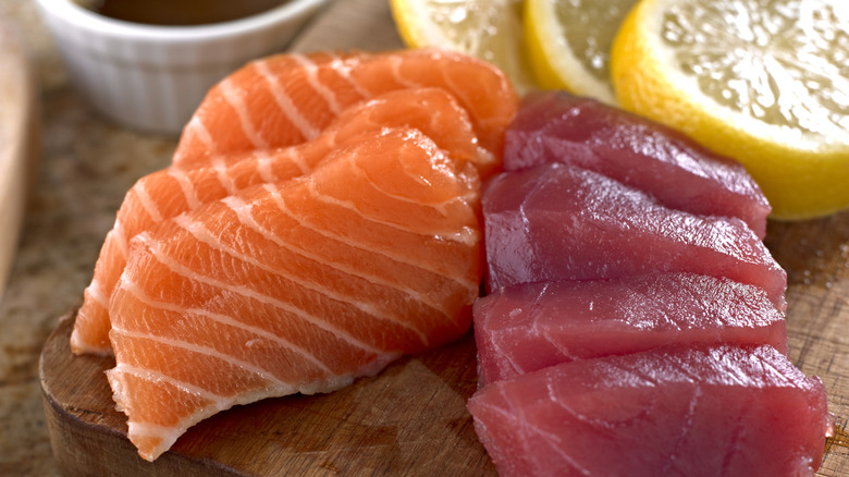 Thick cuts of salmon and tuna sashimi on a wooden cutting board.