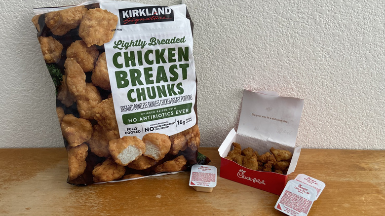 unopened Costco nugget bag beside opened Chick-fil-A nugget box, next to three sauces