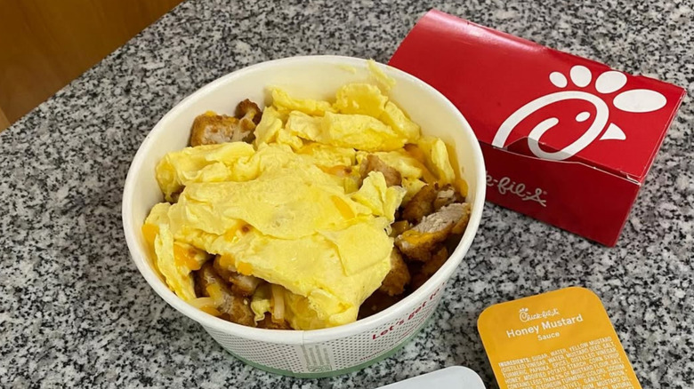A Chick-fil-A breakfast bowl with sauces on a table.