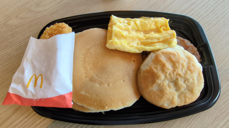 McDonald's big breakfast with hot cakes in a black plastic container.