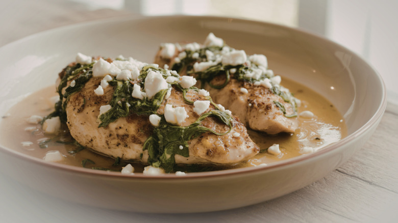 pan-seared chicken breasts with feta cheese and spinach in a beige bowl