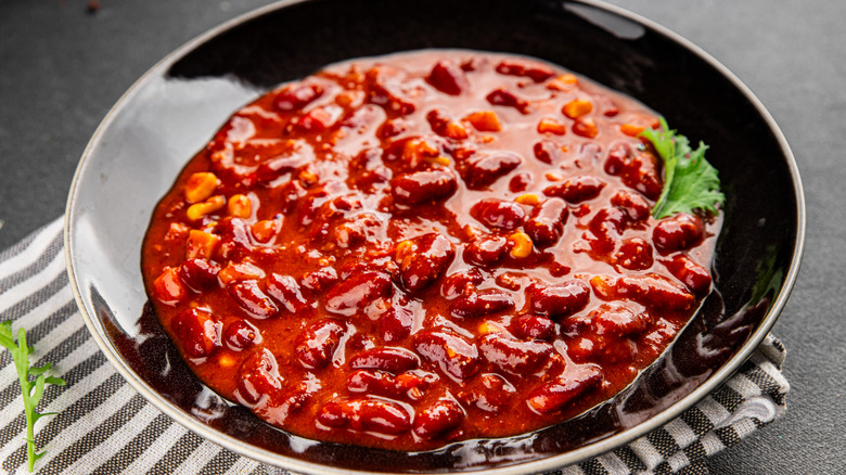 A bowl of chili with beans on a striped napkin