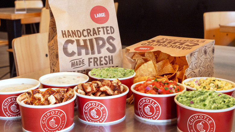 A promotional image for Chipotle's Nacho Hack featuring cups of sauces and protein