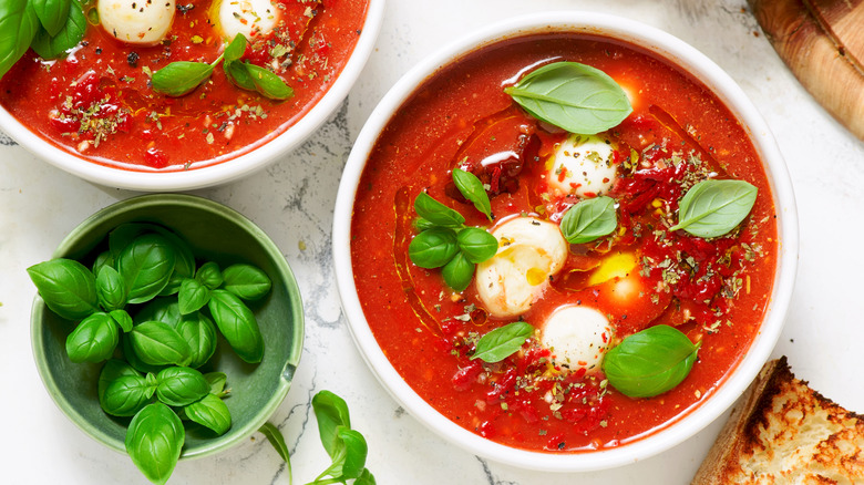 Tomato soup topped with balls of fresh mozzarella, fresh basil leaves, and dried Italian seasoning