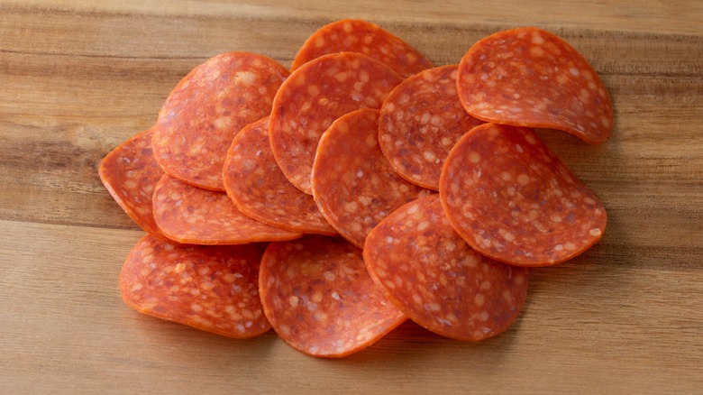 Pepperoni slices on a wood surface