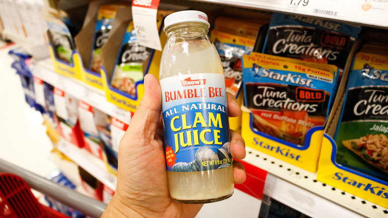 Hand holding bottle of clam juice in store