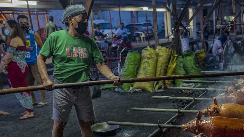multiple lechon being roasted over coals