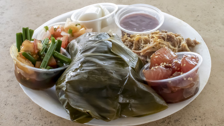 Full platter of Hawaiian dishes including fish, poi, vegetables, and coconut haupia