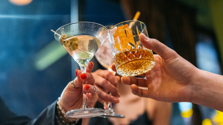 Hands toasting with martini and glass of whiskey