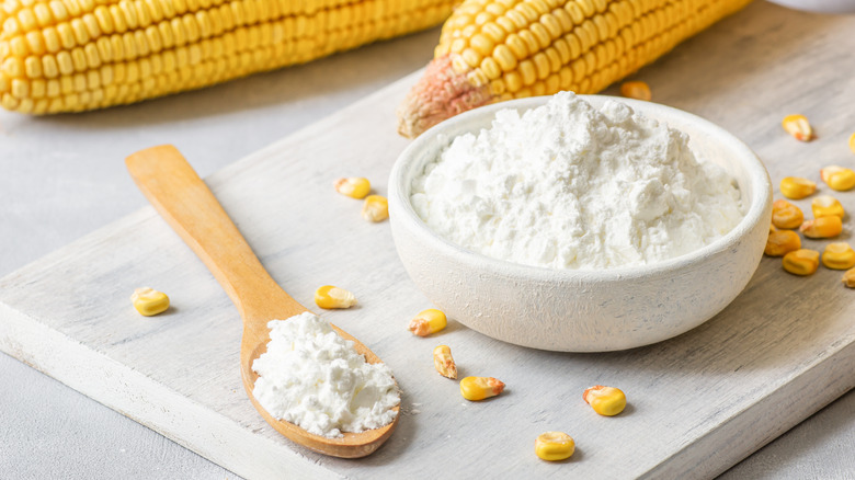 A bowl of cornstarch alongside corn cobs