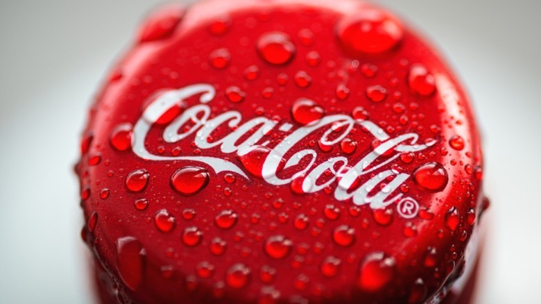 A Coca-Cola bottle cap with water droplets on it.