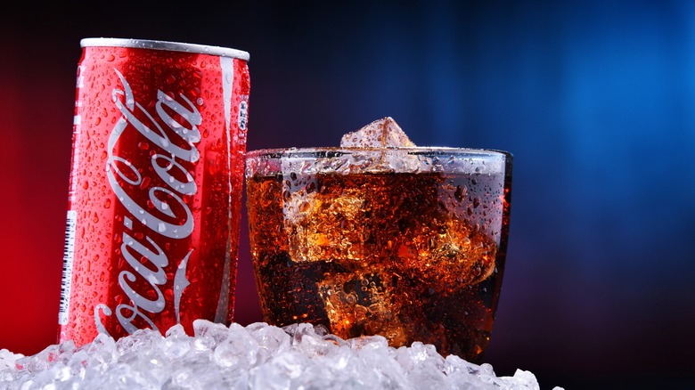 A can and glass of Coca-Cola on ice