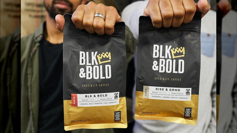 Two men holding up bags of BLK & Bold ground coffee co-owned by Deion Sanders