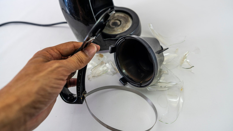 Hand holding broken coffee maker part