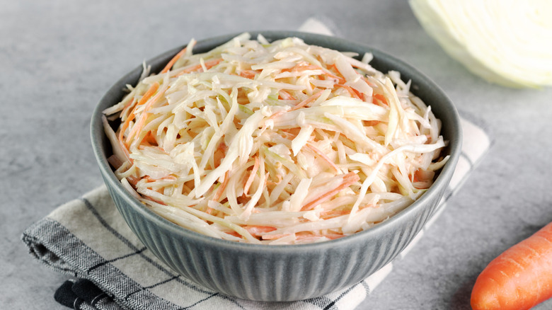 Coleslaw in a ceramic bowl on top of a cloth napkin