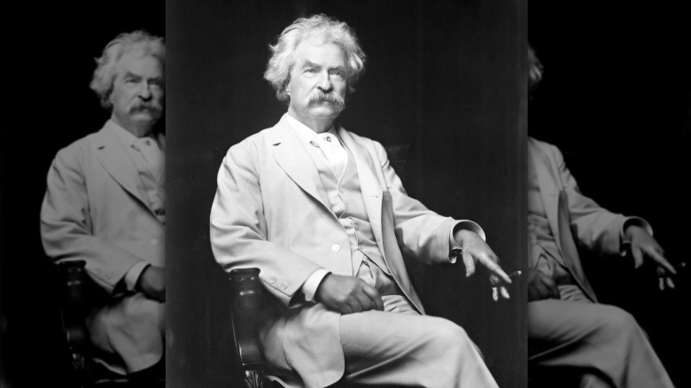 Mark Twain in a white suit posing for a photograph.