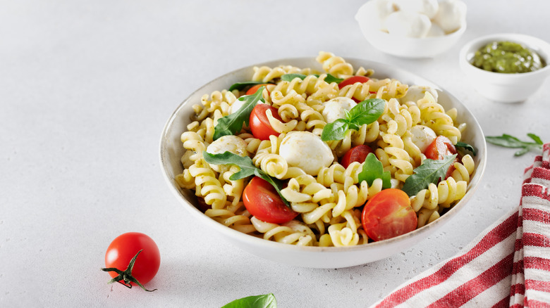 Cold Italian pasta salad with mozzarella balls, cherry tomatoes, basil, and fusili pasta