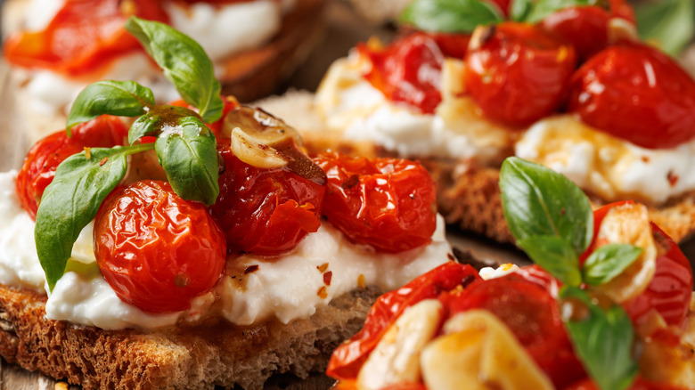 Garlic bread topped with cheese, roasted tomatoes, and basil.