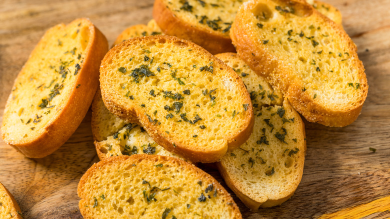 Slices of garlic bread on a wooden cutting board.