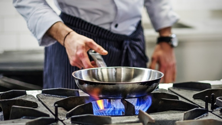 Man preheating stainless steel pan over gas burner