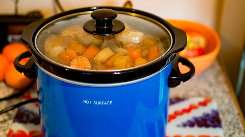 A blue slow cooker filled with beef stew