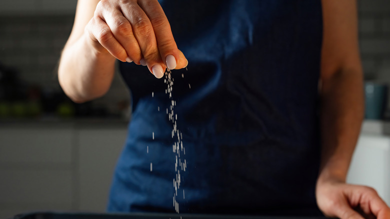 A person adding a pinch of salt to a dish