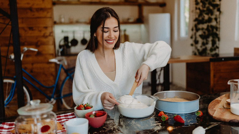 Young woman preparing cheesecake at home