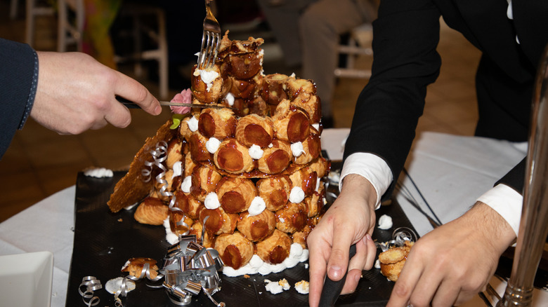 Dessert serving croquembouche with server hands