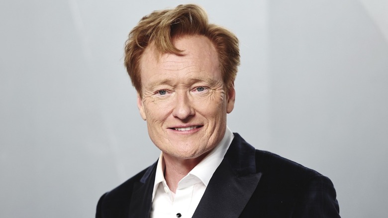 Comedian and talk show host Conan O'Brien in front of a grey background.