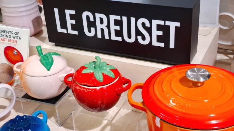 Le Creuset cookware, including Dutch ovens, for sale on a store shelf.
