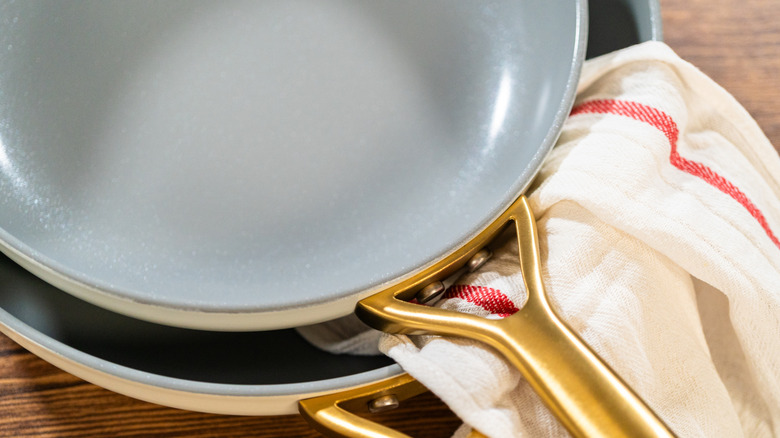Two nonstick pans stacked on top of each other with a dish towel hanging out.