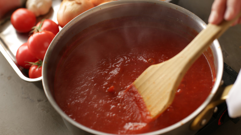 Tomato sauce in sauce pot being stirred with wooden spatula