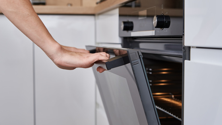 Opening the oven door of a kitchen oven with both hands