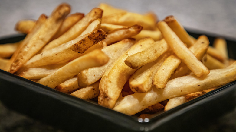 Golden crispy french fries in a black plastic tray
