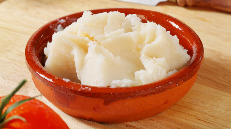 Uncooked lard in a small red ceramic bowl