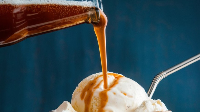 A soda being poured onto a scoop of ice cream