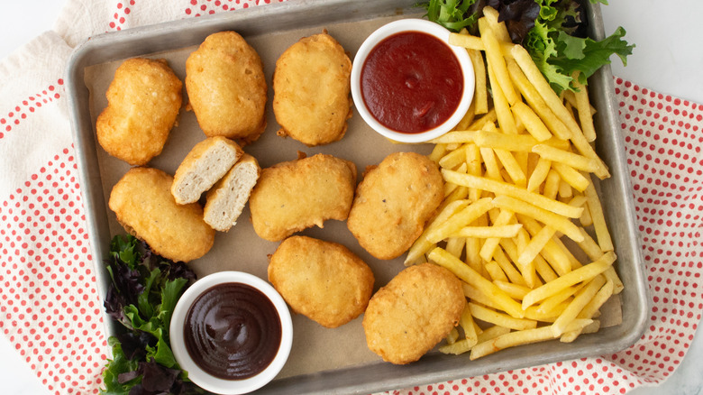 Copycat McDonald's chicken nuggets on serving tray with sauces and fries