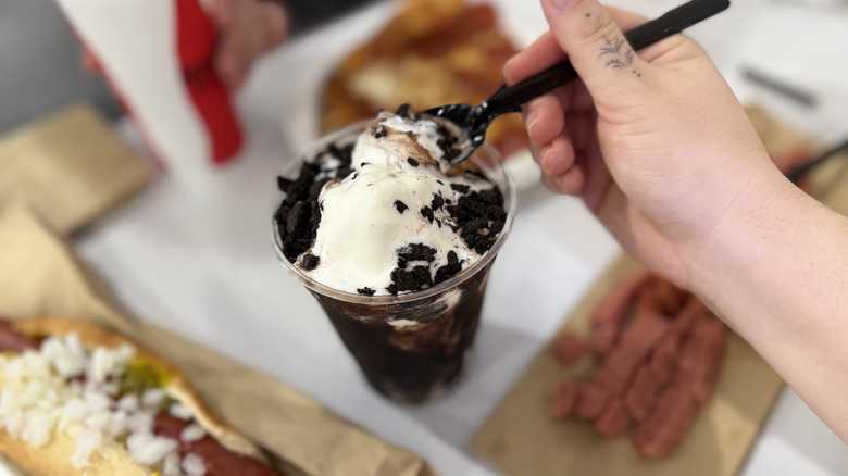 Hand taking a spoonful of Vanilla Cookie Crunch Sundae