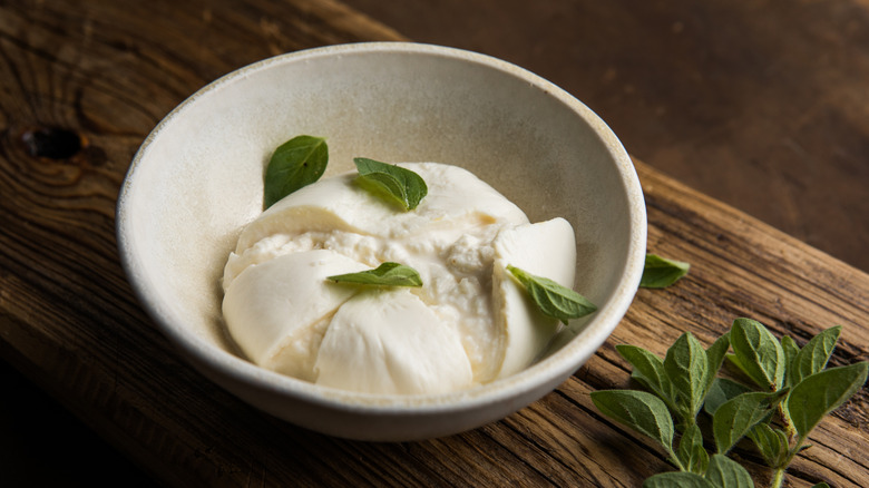 Burrata in bowl with herbs on top.