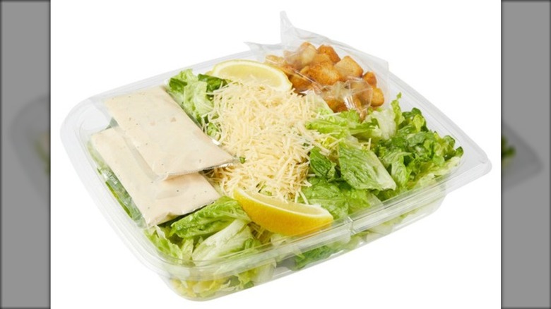 Kirkland Signature Caesar Salad with Caesar Dressing and Croutons on a white background.