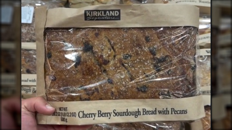 Person holding a loaf of Costco's Kirkland Signature Cherry Berry Sourdough Bread with Pecans