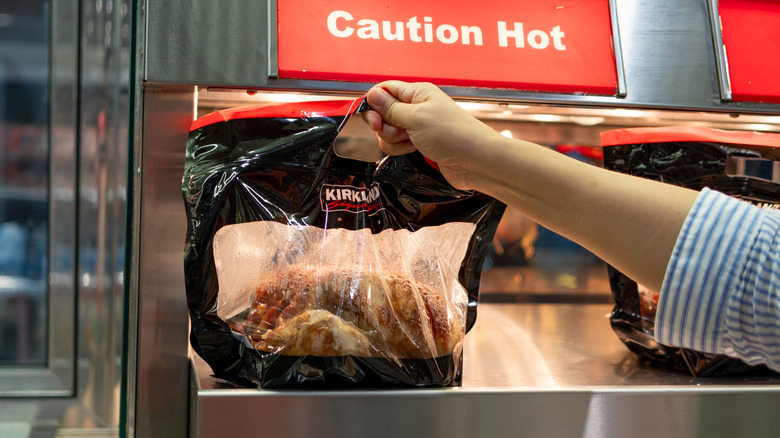 Costco rotisserie chicken being pulled off heating shelf