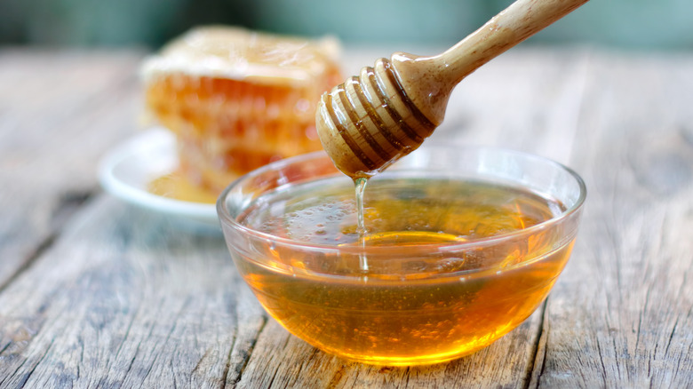 Honey dipper over a small glass bowl of honey