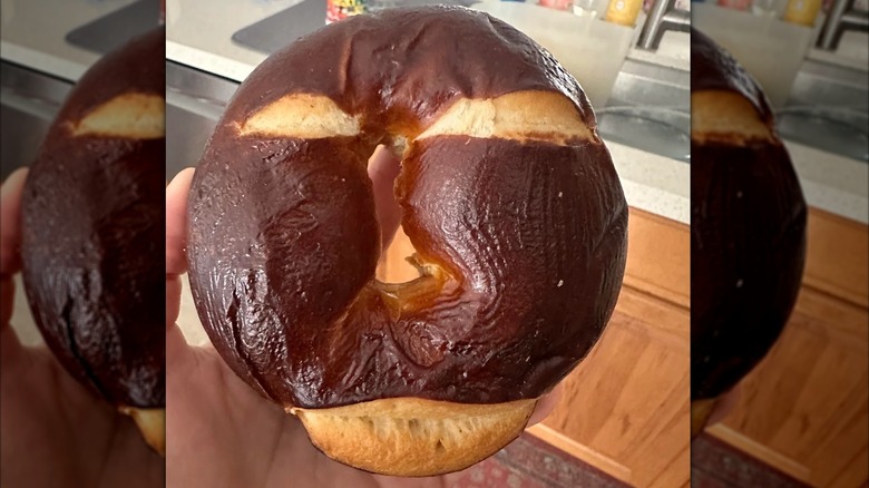 Hand holding a whole Costco pretzel bagel