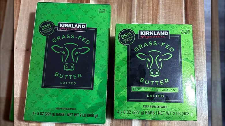 Two differently sized packages of Kirkland Signature grass-fed butter on wood surface